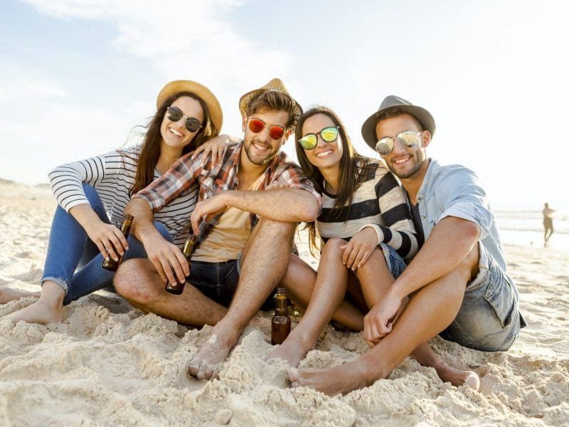 Friends Relaxing Together On Sandy Beach